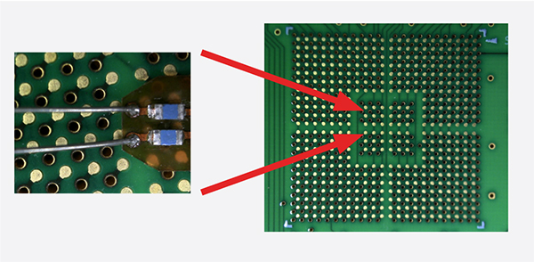 Probe tip and wires next to small test points on the back side of a BGA package.